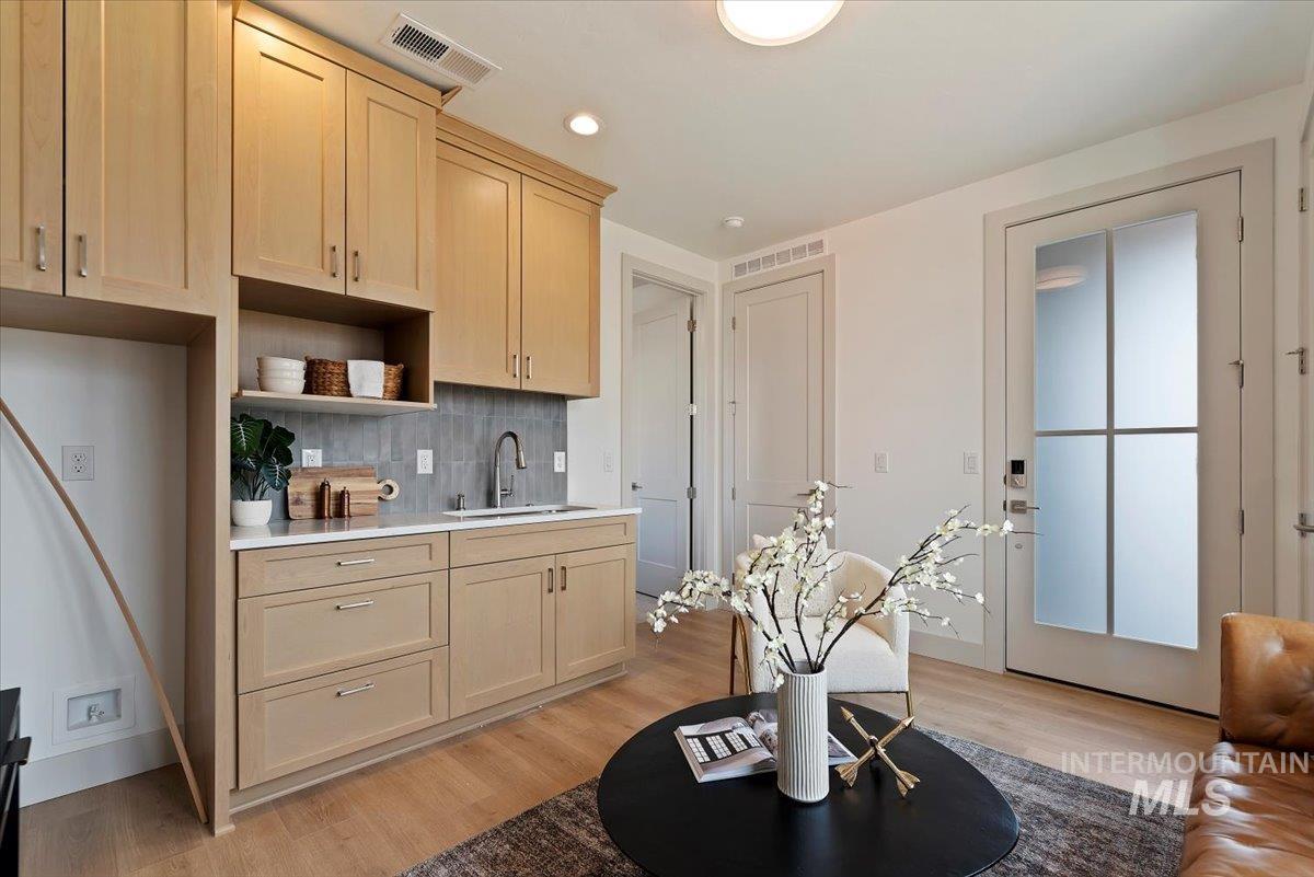 Bar area with light wood-style flooring, light wood finish cabinetry, backsplash, open shelves, and recessed lighting