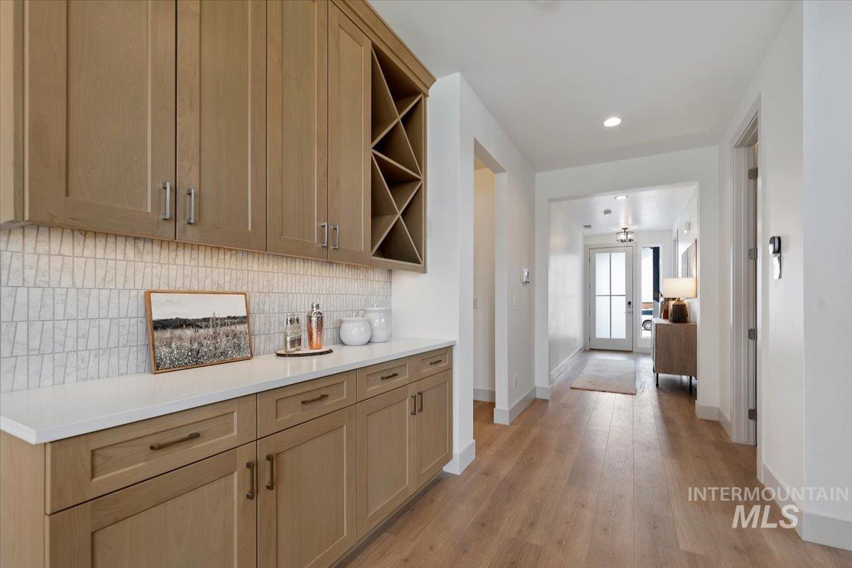 Bar with open shelves, light wood-style flooring, tasteful backsplash, light stone counters, and recessed lighting