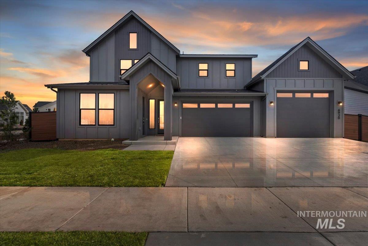Modern farmhouse with board and batten siding, a lawn, driveway, and an attached garage