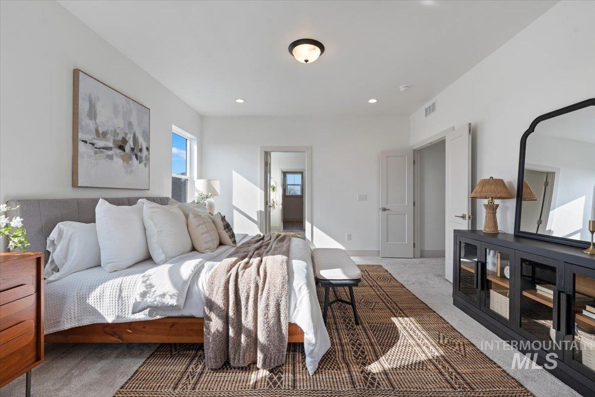 Carpeted bedroom with ensuite bathroom and recessed lighting