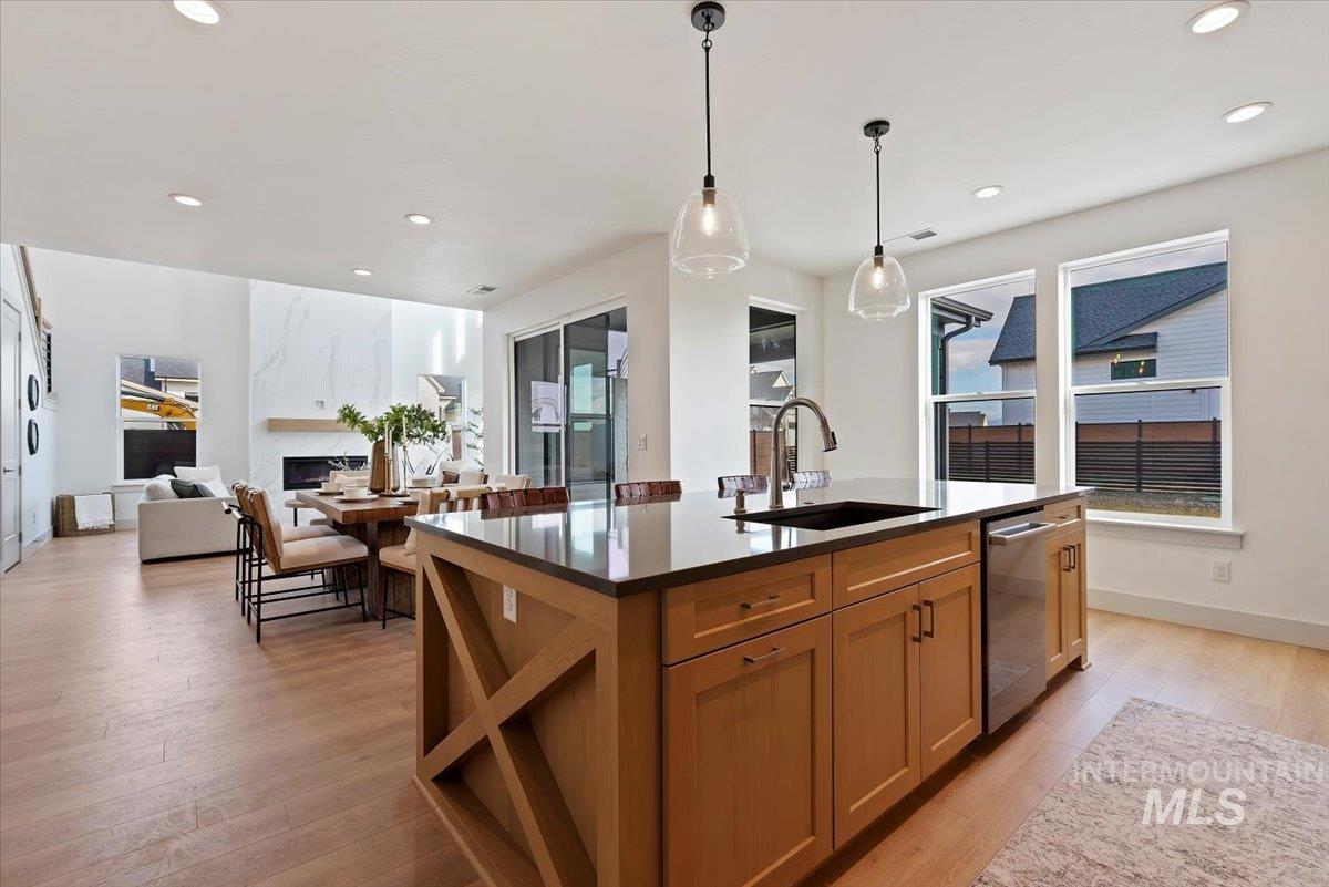 Kitchen with a kitchen island with sink, light wood-style flooring, open floor plan, a fireplace, and pendant lighting