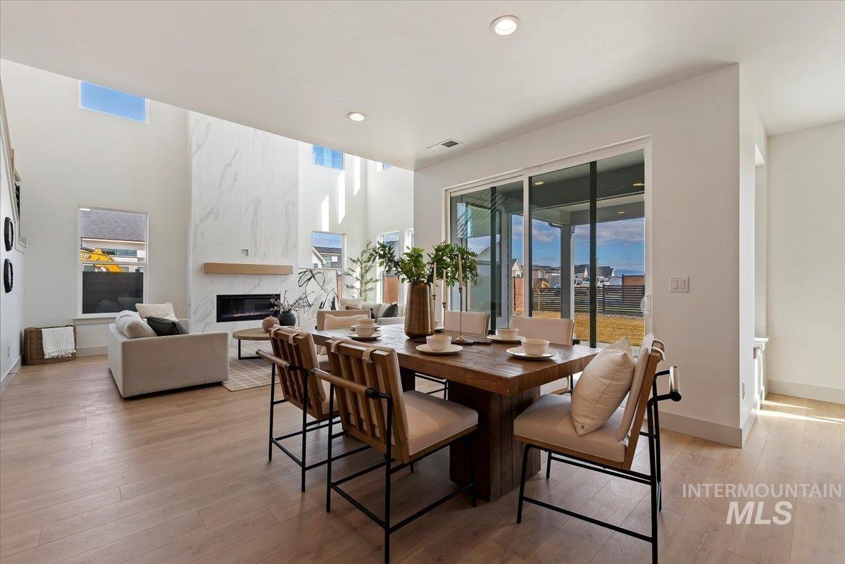 Dining area with light wood-style floors, a high end fireplace, and recessed lighting
