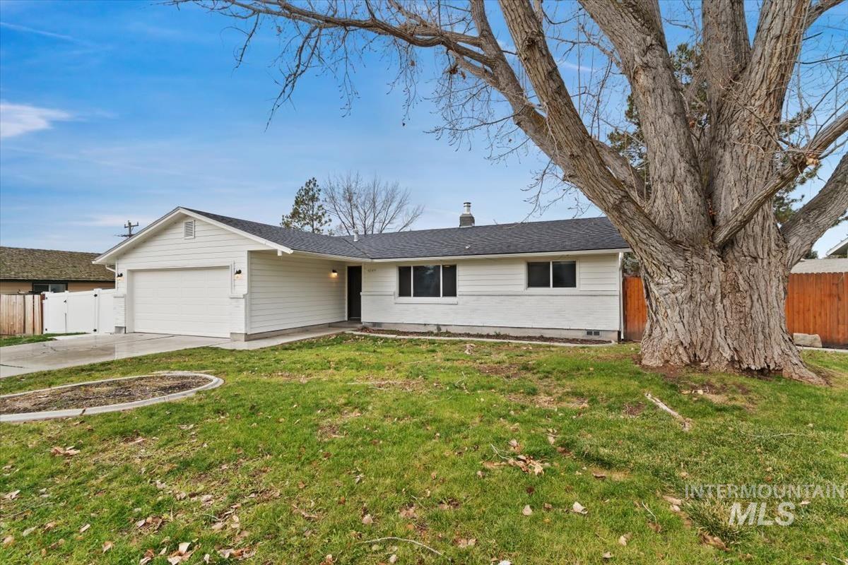 Ranch-style home with a chimney, driveway, a garage, and a shingled roof