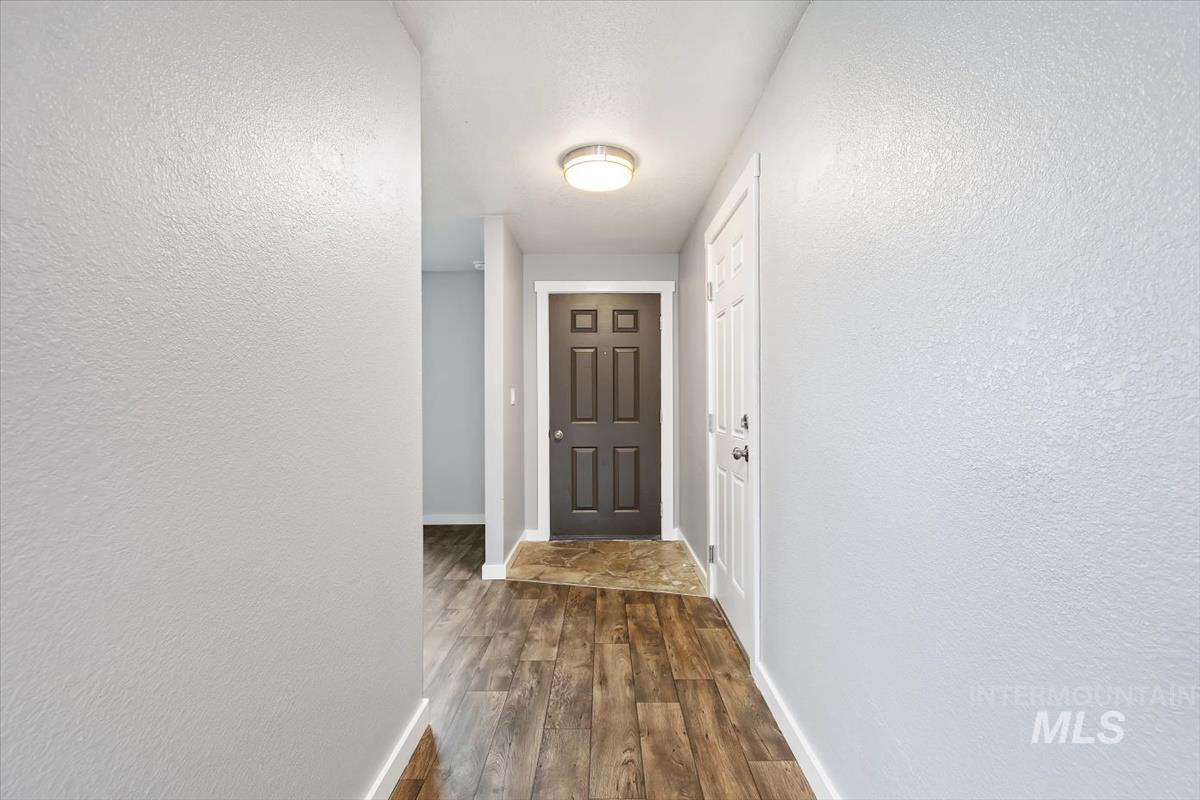 Doorway with a textured wall and wood finished floors