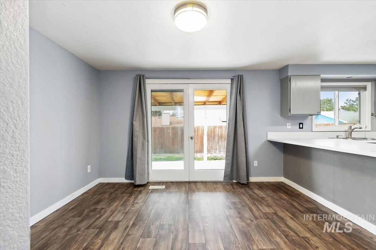 Unfurnished dining area featuring dark wood-style flooring and baseboards