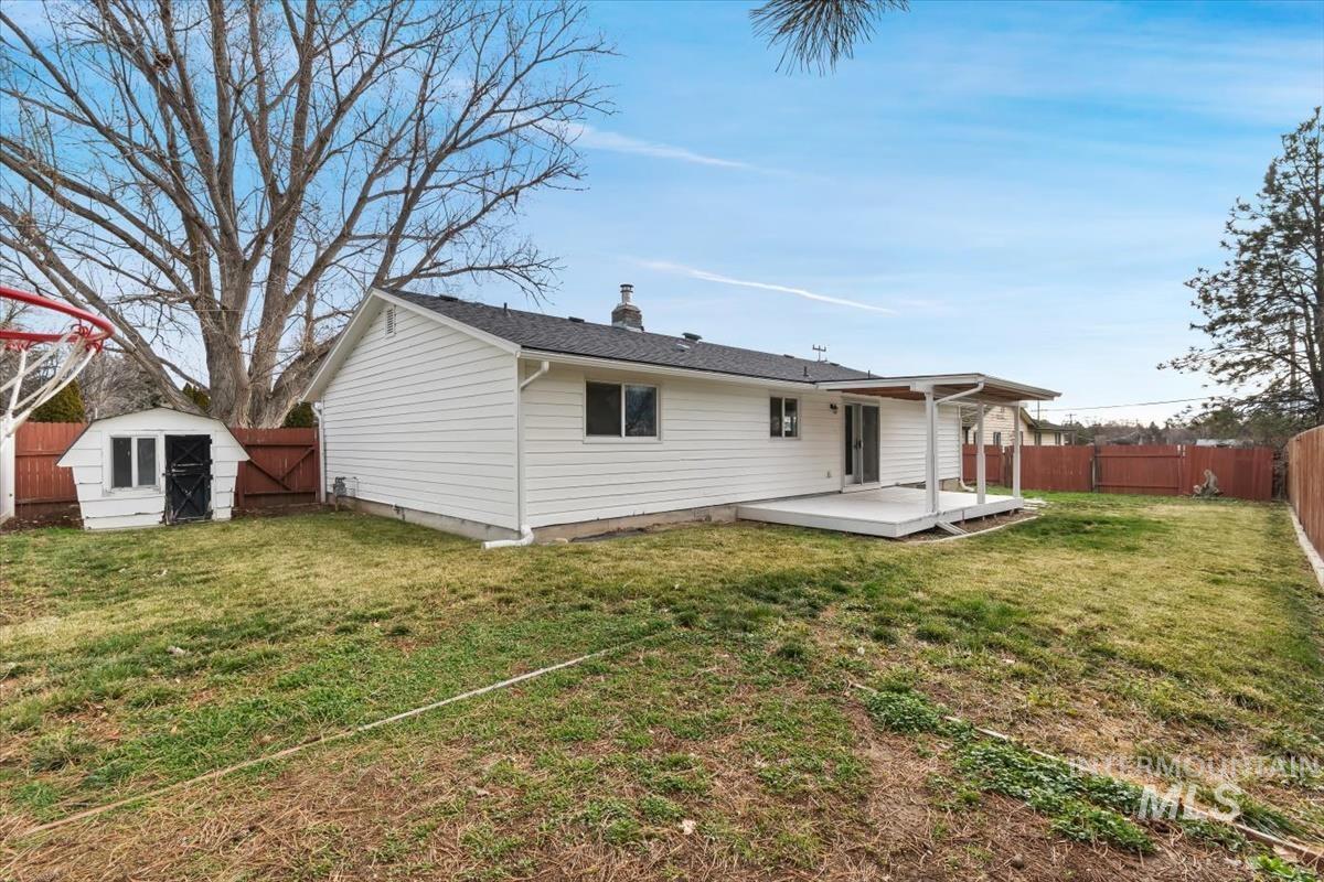Back of property with a fenced backyard, a storage shed, a chimney, and a deck