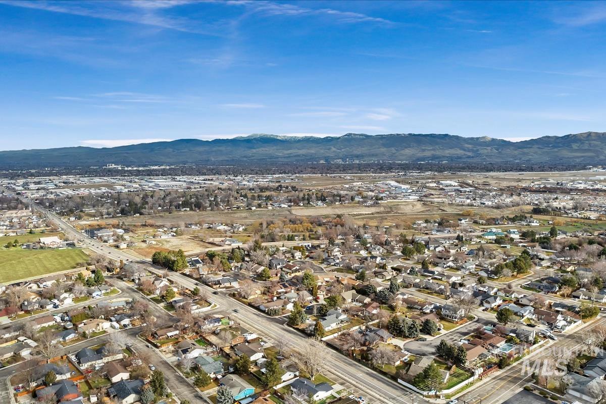 Aerial view of property and surrounding area with a mountain backdrop and nearby suburban area