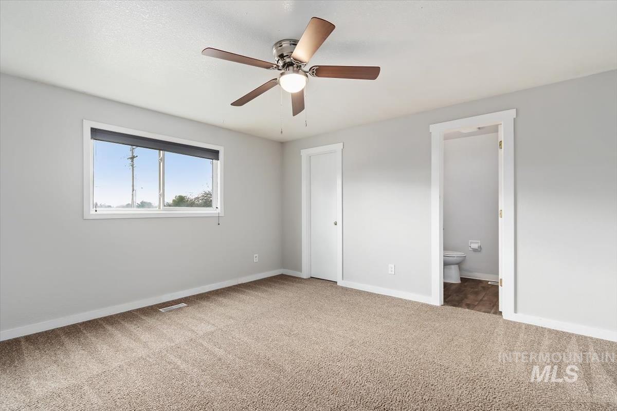 Unfurnished bedroom with carpet flooring, ceiling fan, and connected bathroom