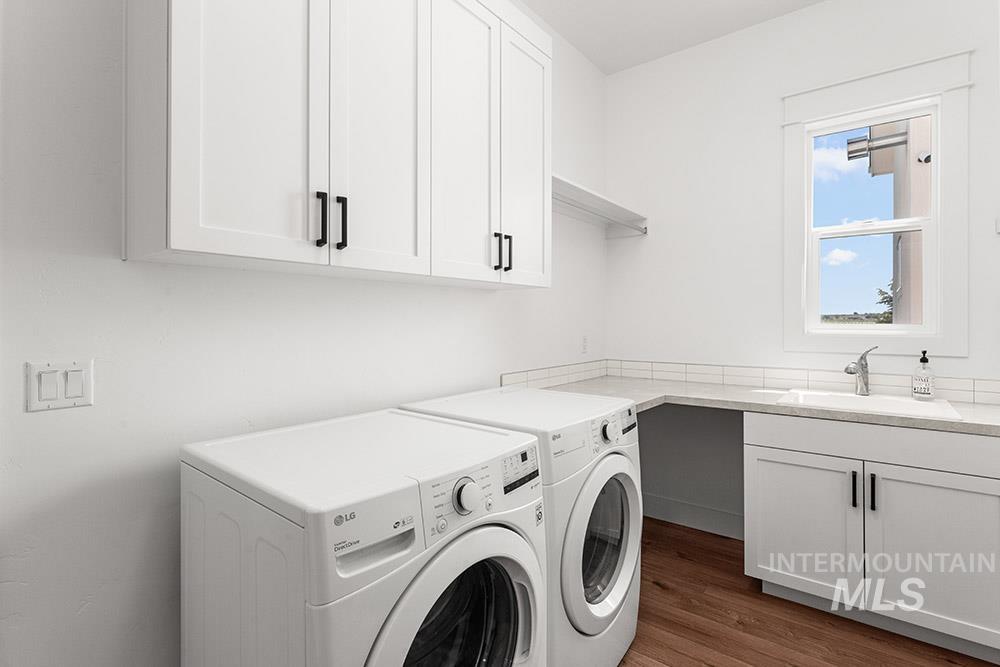Washroom featuring washer and clothes dryer, cabinet space, and wood finished floors