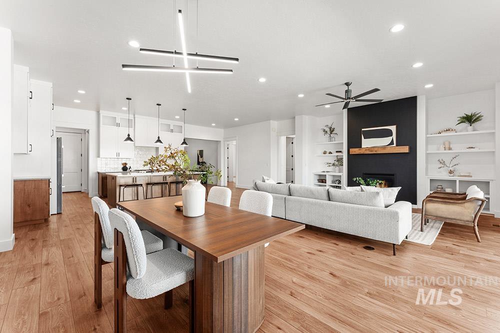Dining space featuring a ceiling fan, recessed lighting, light wood-style flooring, built in shelves, and a fireplace