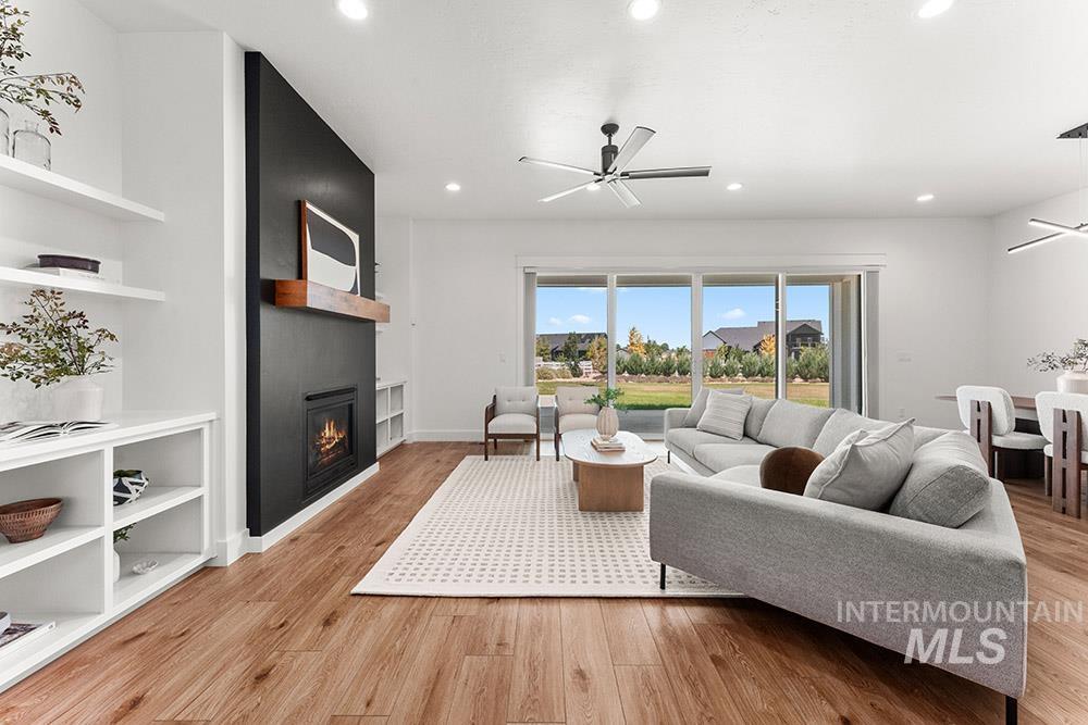 Living room featuring a ceiling fan, a large fireplace, light wood-type flooring, and recessed lighting