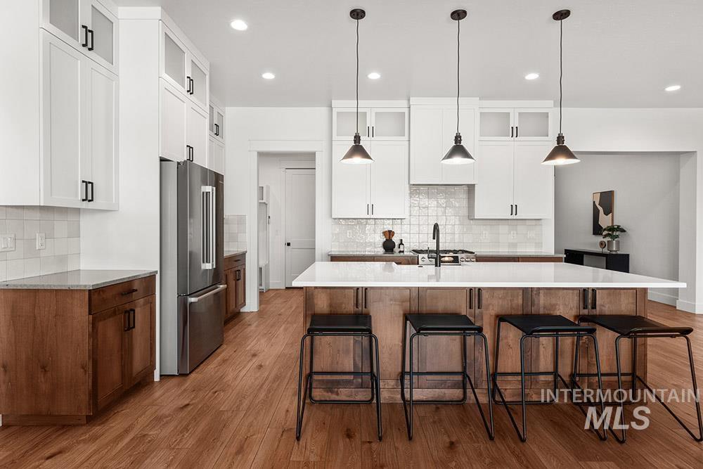 Kitchen featuring high quality fridge, decorative backsplash, wood finished floors, and recessed lighting