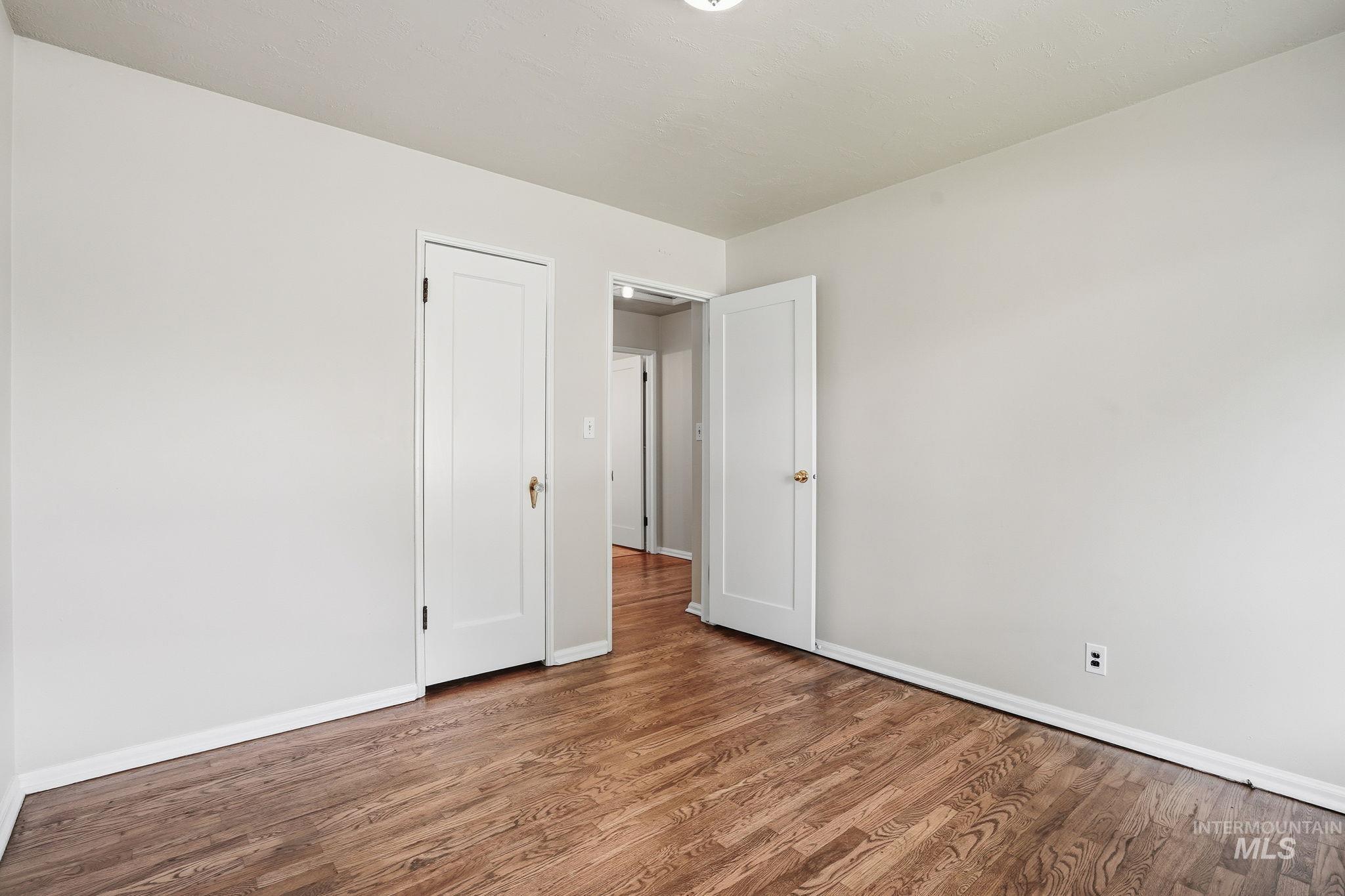 Unfurnished bedroom featuring wood finished floors and baseboards