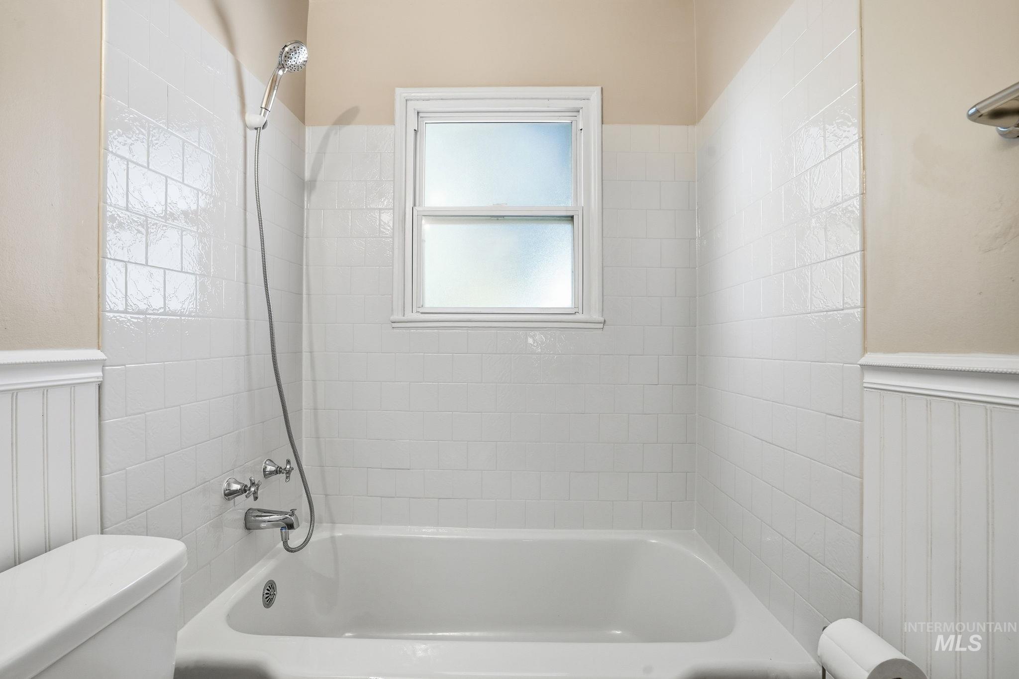 Bathroom featuring a wainscoted wall and shower / tub combination