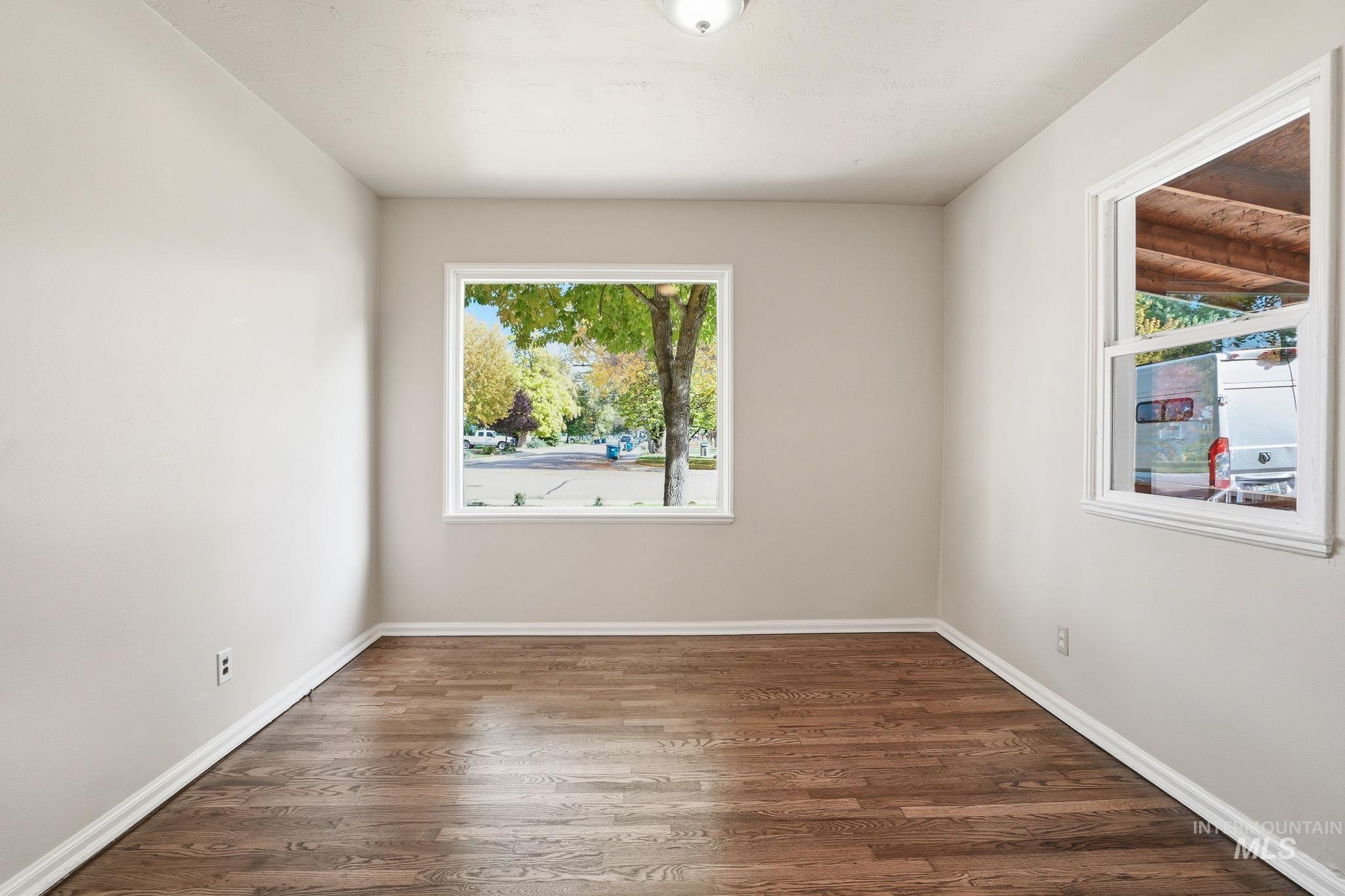Spare room featuring dark wood-type flooring and healthy amount of natural light