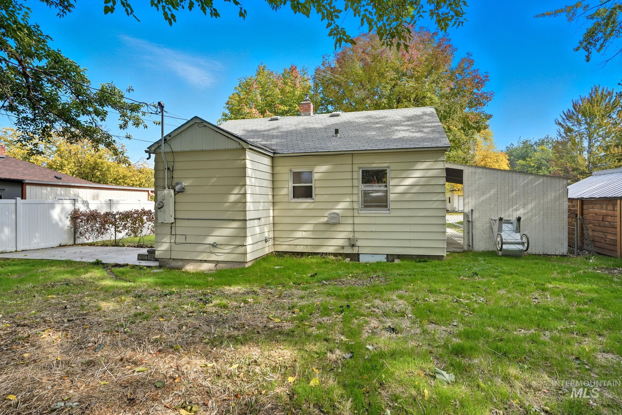 Back of house featuring a chimney, roof with shingles, and a patio