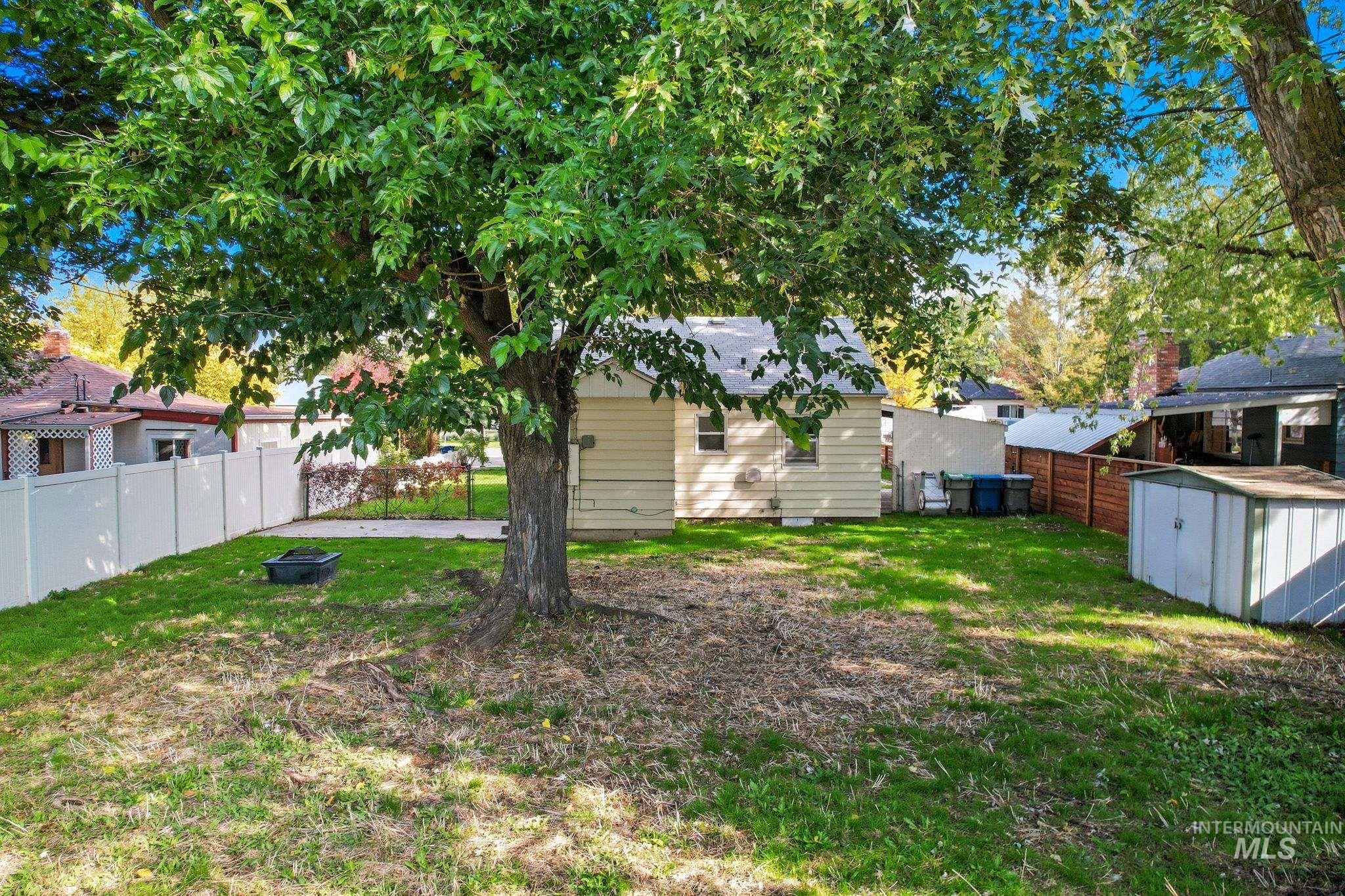 Fenced backyard featuring a storage unit
