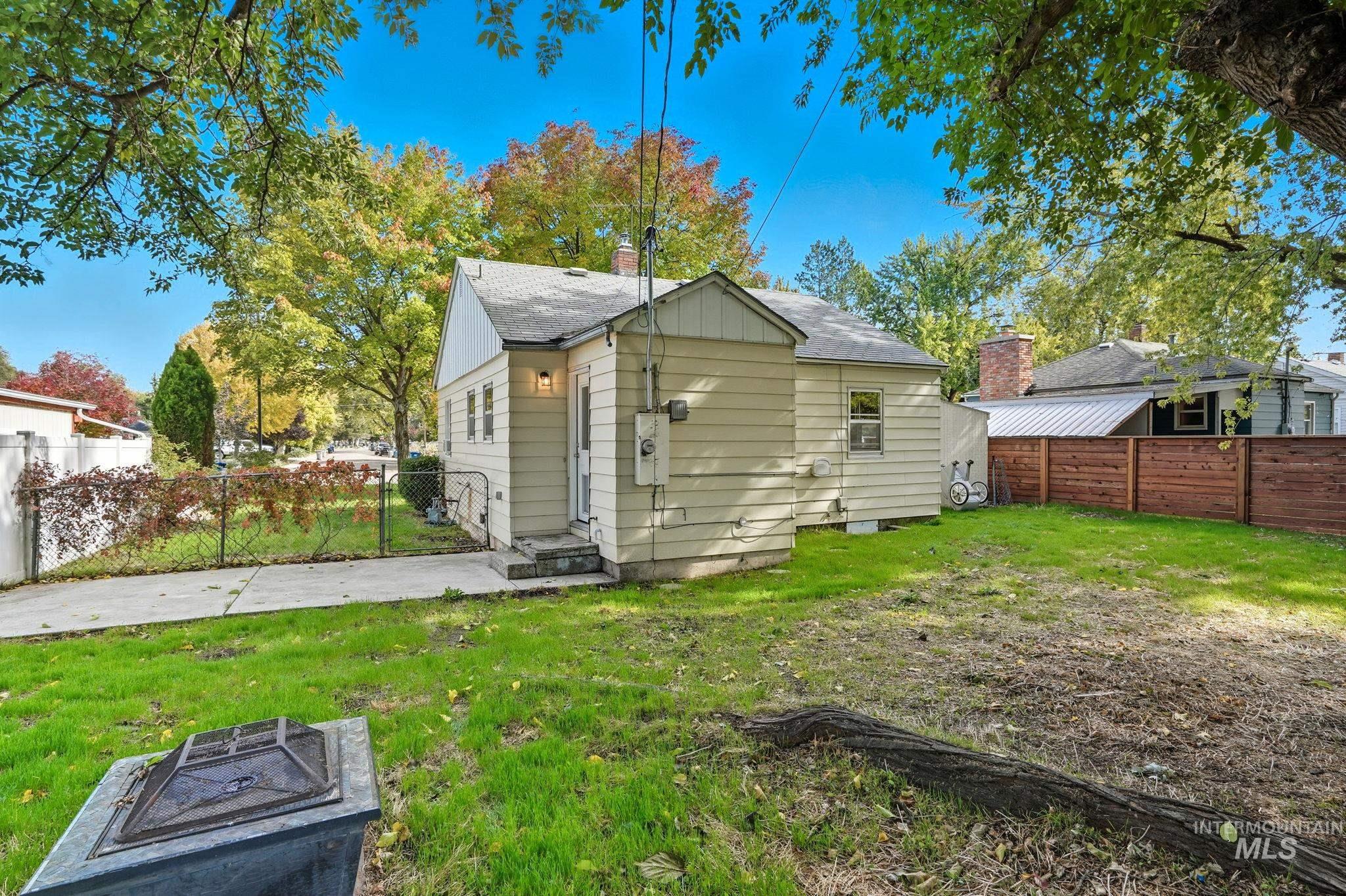 Back of property with a fenced backyard, a fire pit, a shingled roof, and a chimney