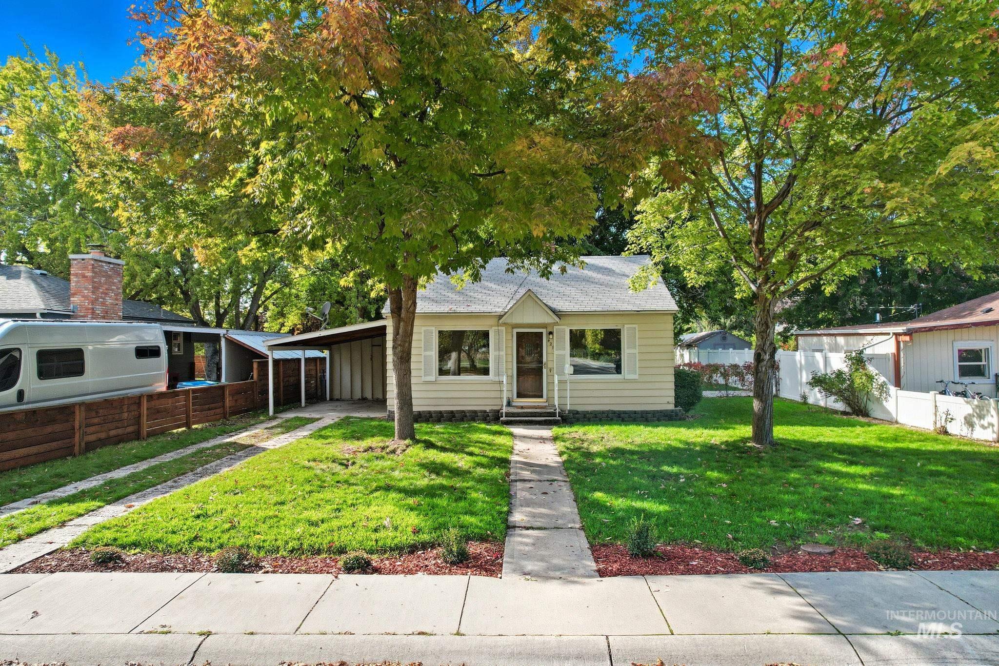 Bungalow-style home featuring a shingled roof, an attached carport, and driveway
