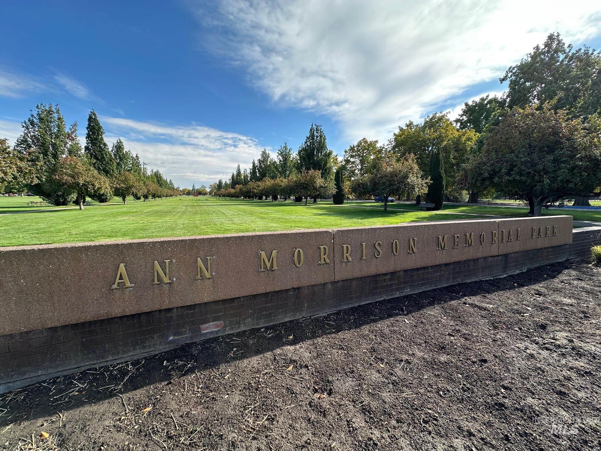 Community sign with a yard and view of scattered trees