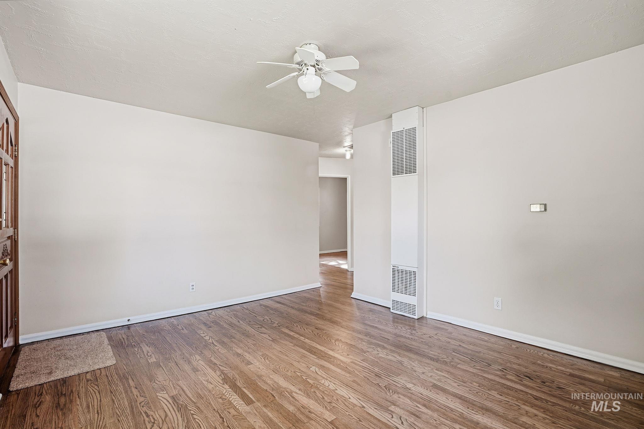 Unfurnished room with wood finished floors, a heating unit, and ceiling fan
