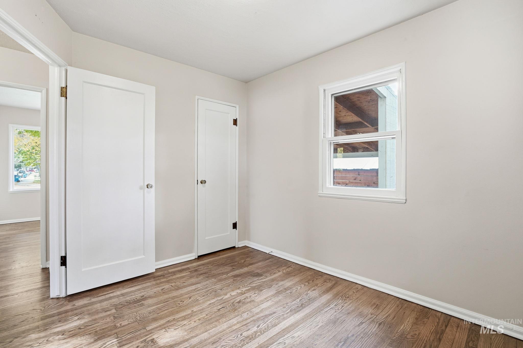 Unfurnished bedroom with light wood-style floors and multiple windows