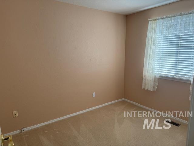 Unfurnished room with baseboards and light carpet