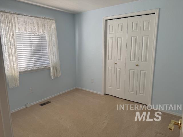 Unfurnished bedroom featuring light carpet and a closet