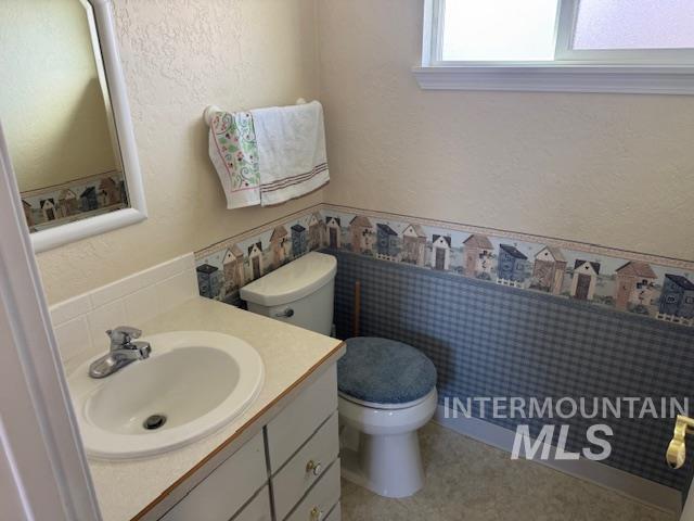 Half bathroom with a textured wall, vanity, and light floors