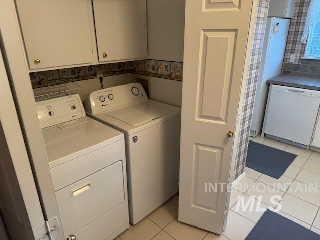 Laundry area with light tile patterned flooring, independent washer and dryer, and cabinet space