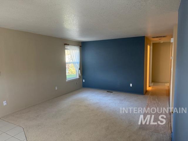 Unfurnished room with a textured ceiling and light carpet