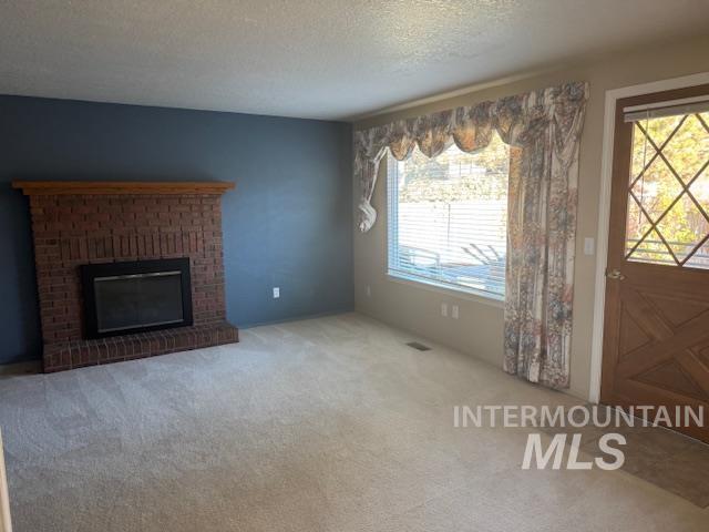 Unfurnished living room with a fireplace, a textured ceiling, and carpet flooring