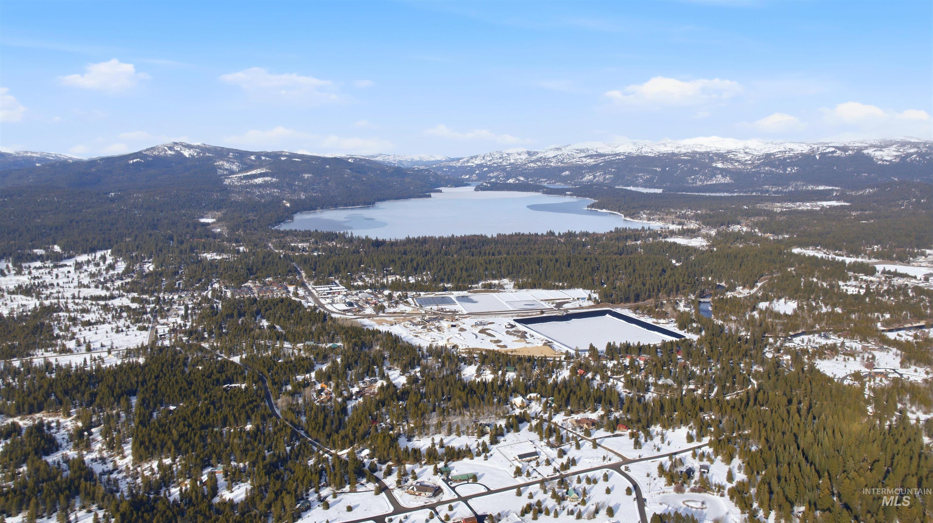 Snowy aerial view with a water and mountain view and a wooded view
