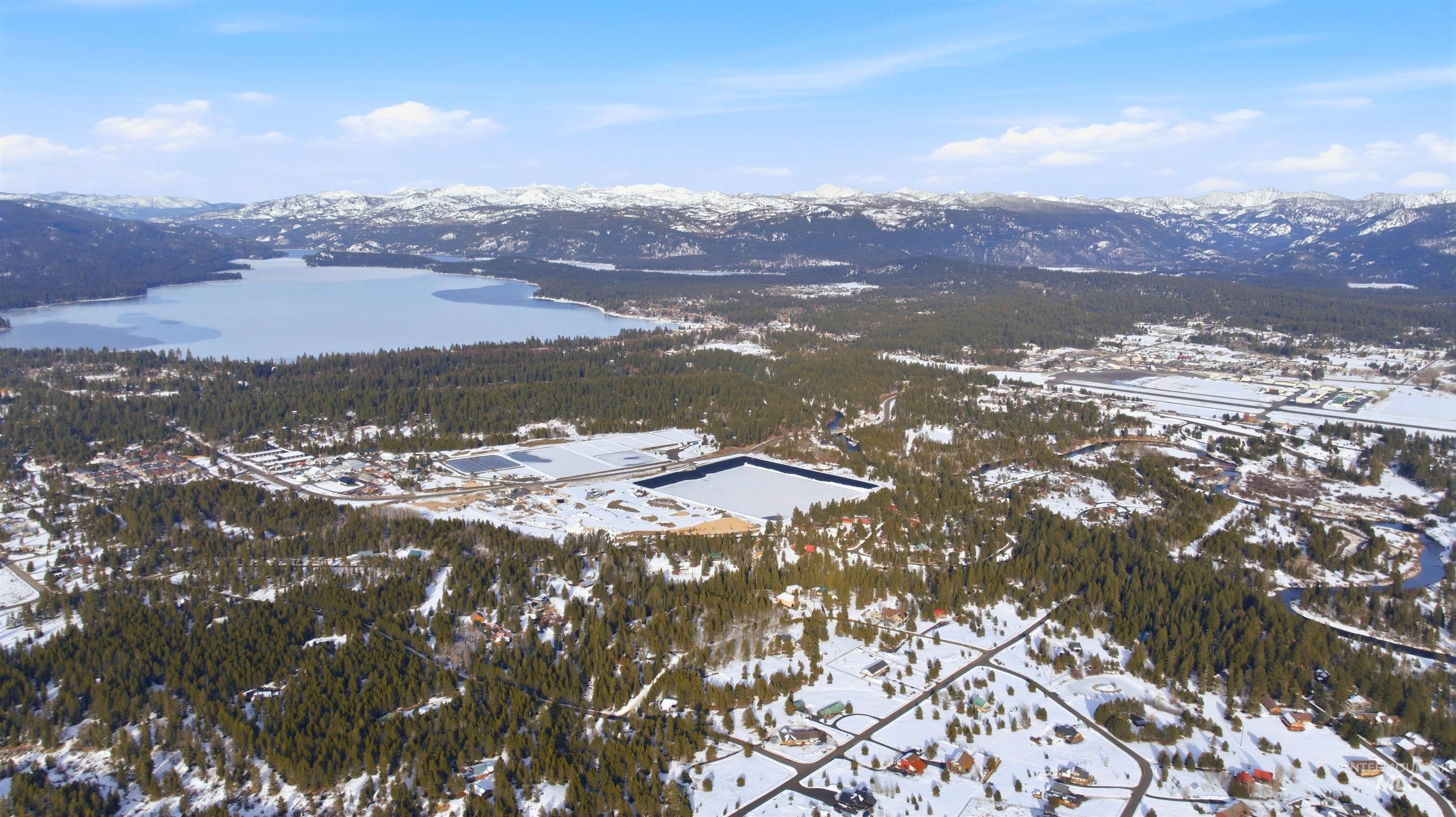 Snowy aerial view featuring a water and mountain view and a view of trees