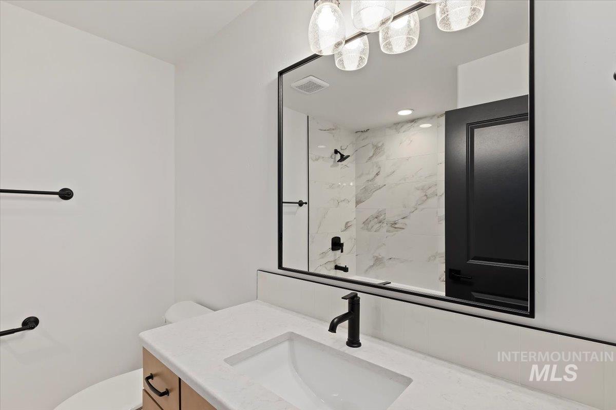Bathroom featuring vanity and a marble finish shower