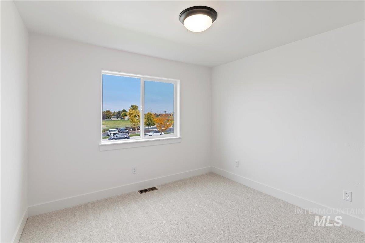 Unfurnished room featuring light carpet and baseboards