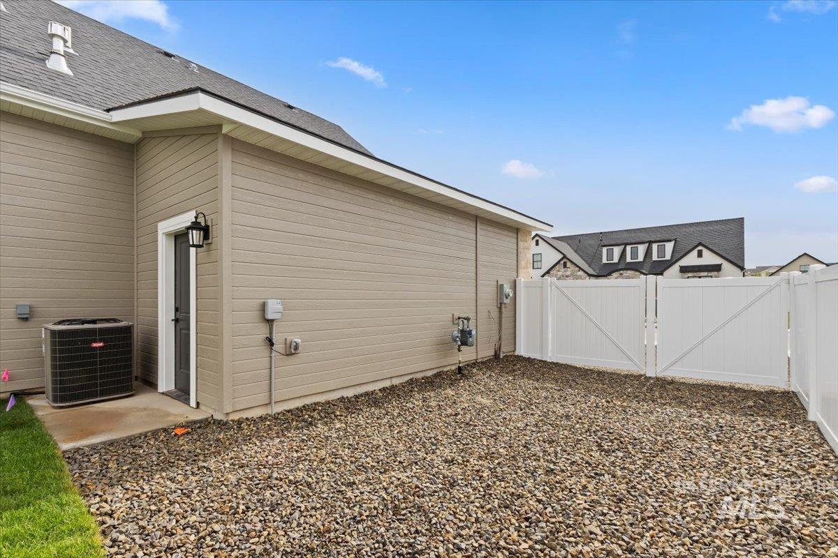 View of side of property featuring a gate and roof with shingles