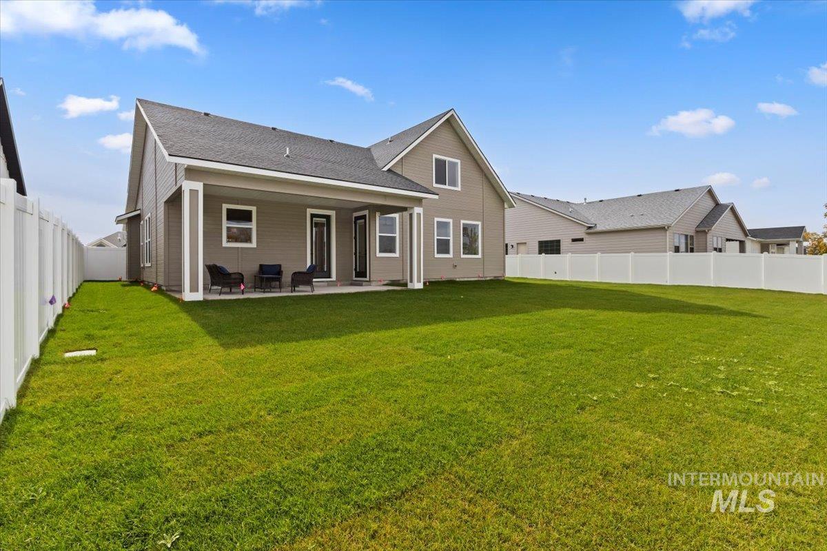 Rear view of house featuring a fenced backyard, a patio, and roof with shingles
