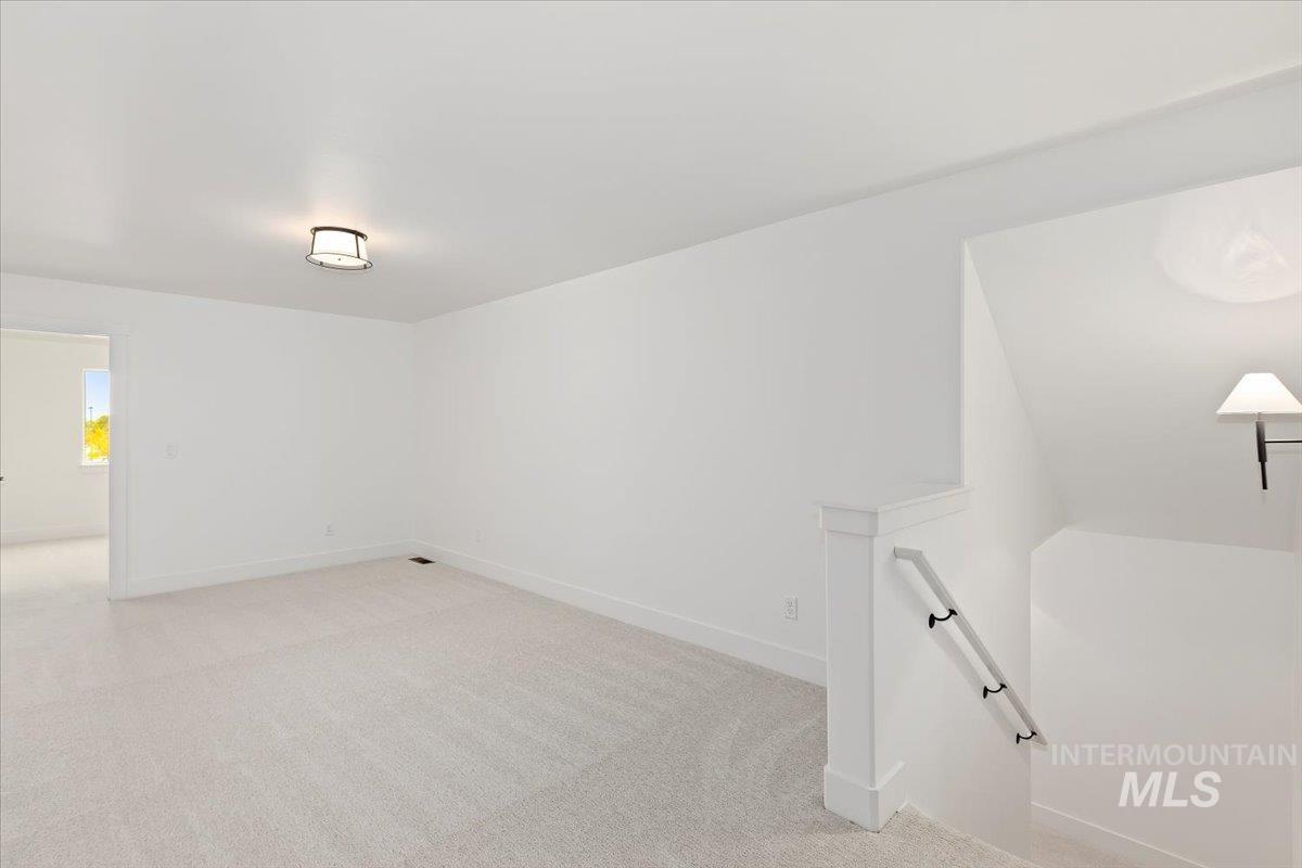 Bonus room with light colored carpet and baseboards
