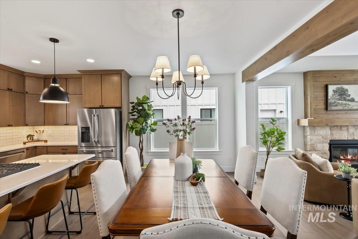 Dining space with plenty of natural light, a fireplace, a chandelier, beam ceiling, and recessed lighting