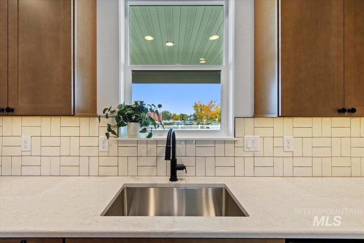 Kitchen featuring decorative backsplash, light stone counters, and recessed lighting