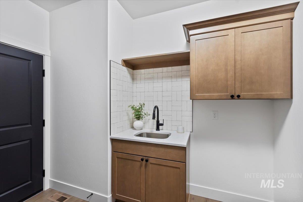 Kitchen featuring light wood finished floors, light stone counters, and brown cabinetry