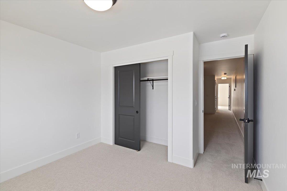 Unfurnished bedroom featuring light carpet and a closet