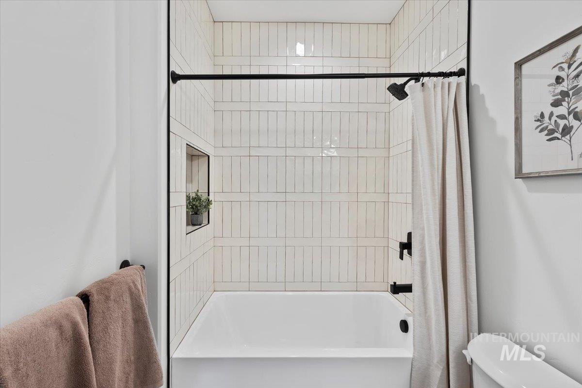 Bathroom featuring shower / tub combo with curtain and toilet