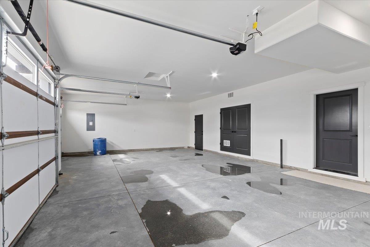 Garage featuring electric panel and a garage door opener