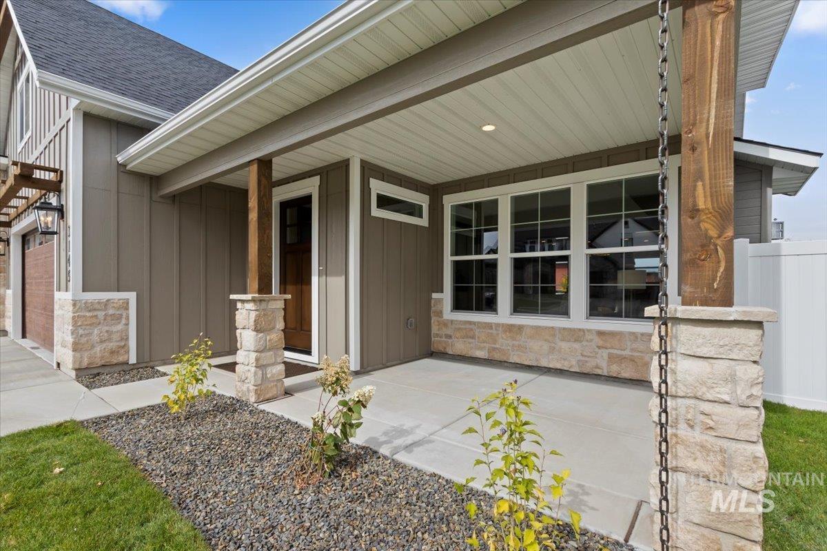 View of exterior entry featuring board and batten siding, stone siding, roof with shingles, and a porch