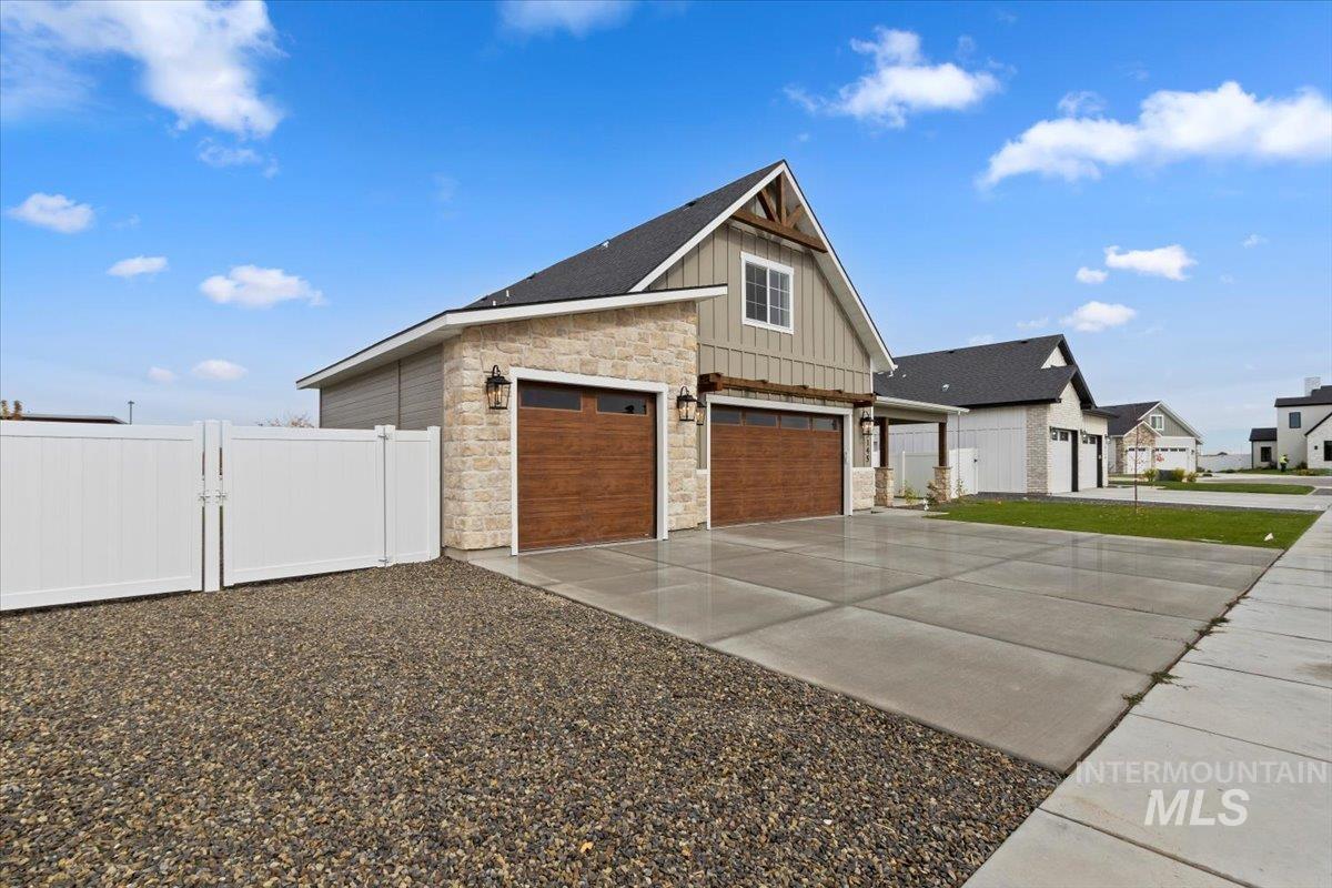 View of property exterior with board and batten siding, driveway, and stone siding