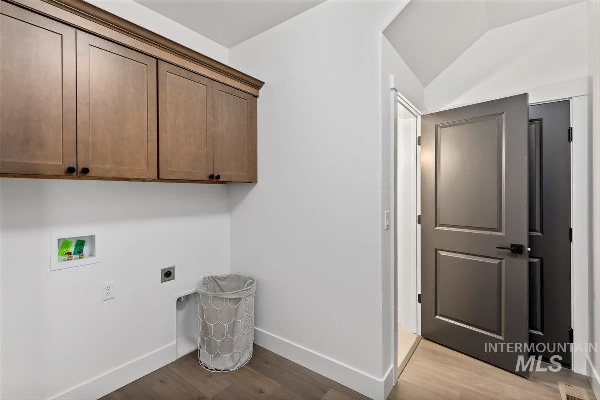 Laundry room with light wood finished floors, electric dryer hookup, cabinet space, washer hookup, and vaulted ceiling