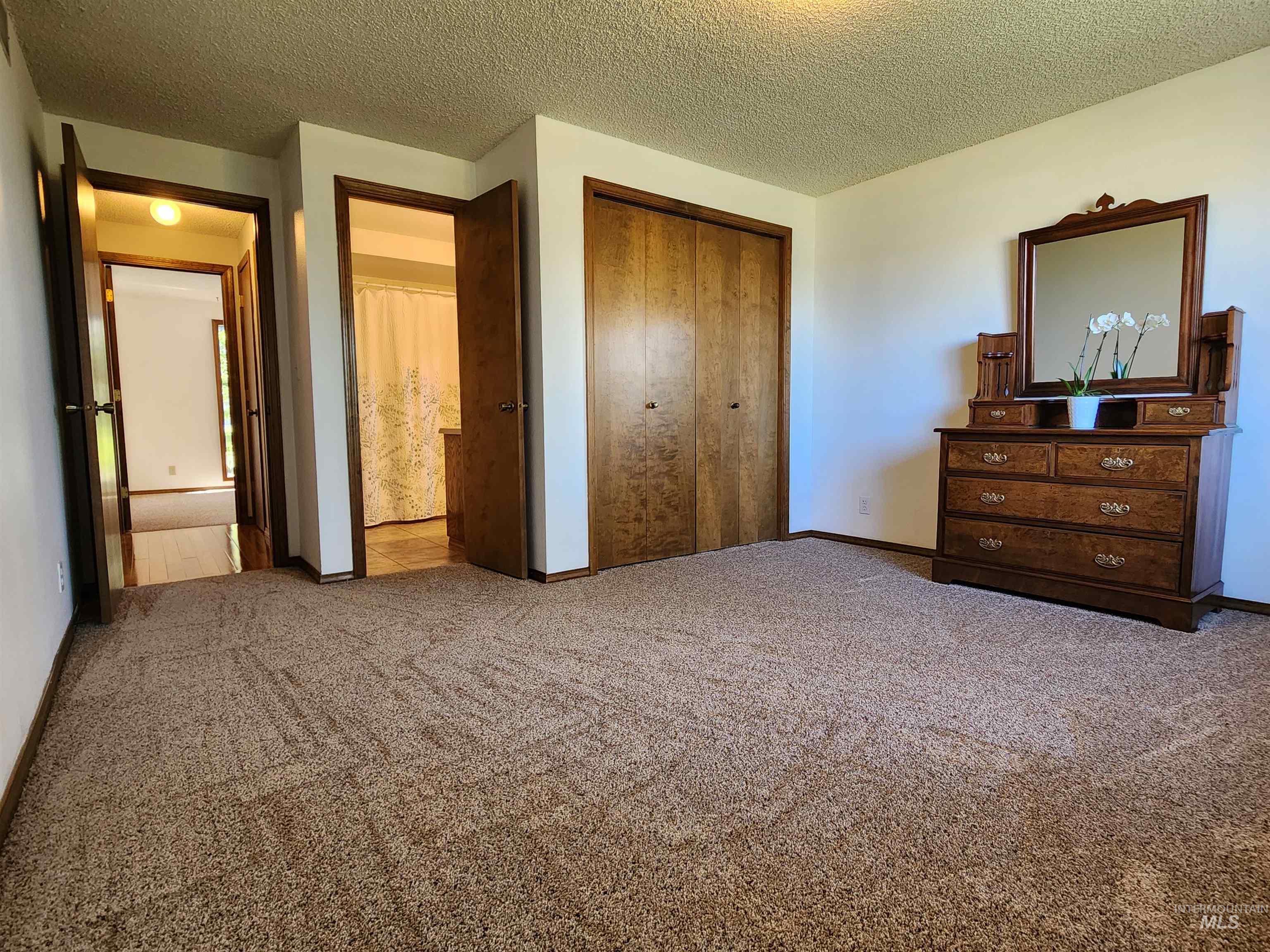 Bedroom with a textured ceiling, carpet flooring, and a closet
