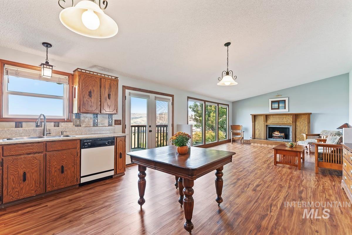 Kitchen featuring brown cabinets, light countertops, dishwasher, french doors, and light wood-style flooring